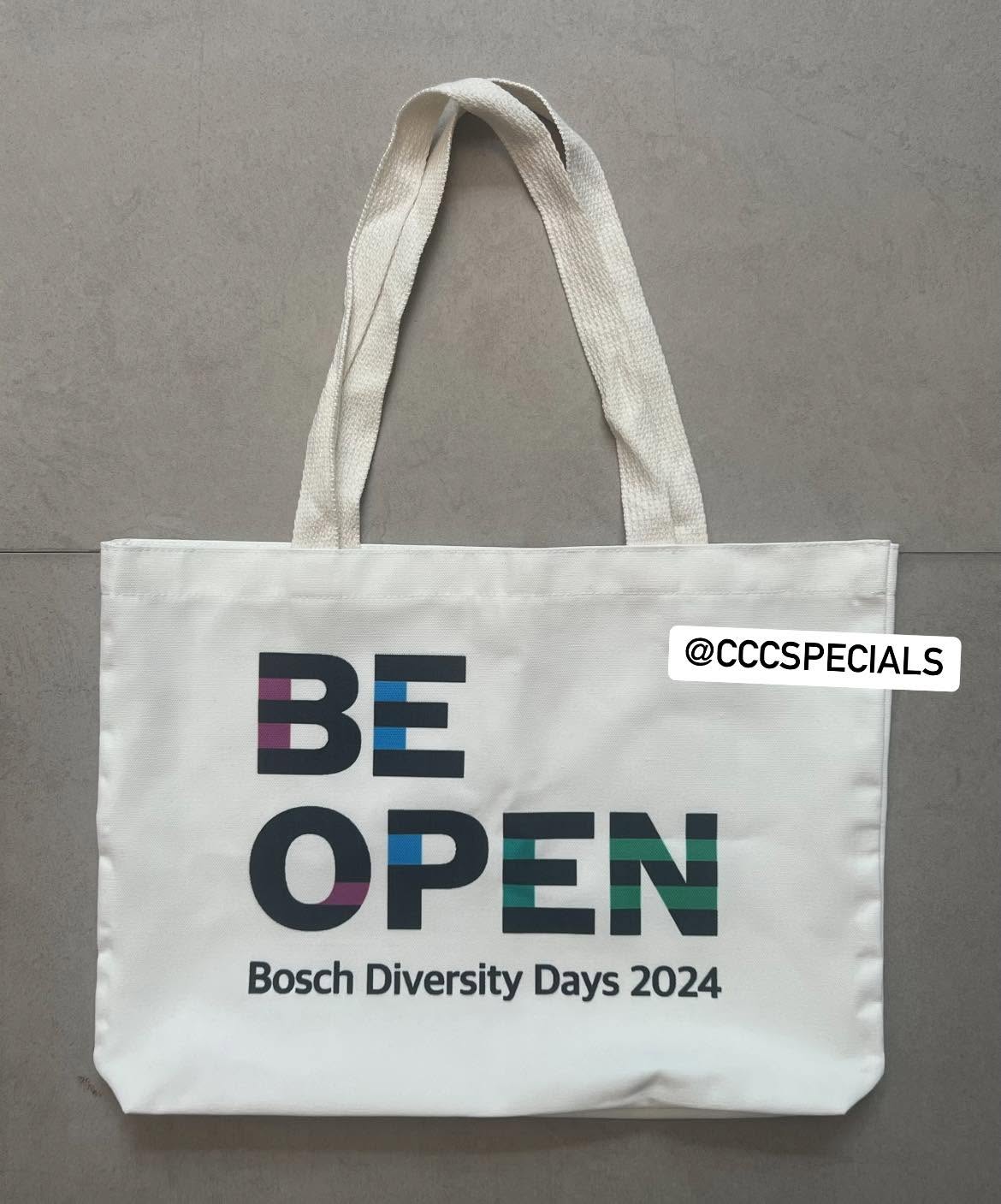 ถุงผ้าแคนวาสสีขาวสกรีนลาย Bosch Diversity Days 2024 ถุงผ้าแคนวาสสีขาวสกรีนข้อความ BE OPEN และ Bosch Diversity Days 2024 วางบนพื้นสีเทา